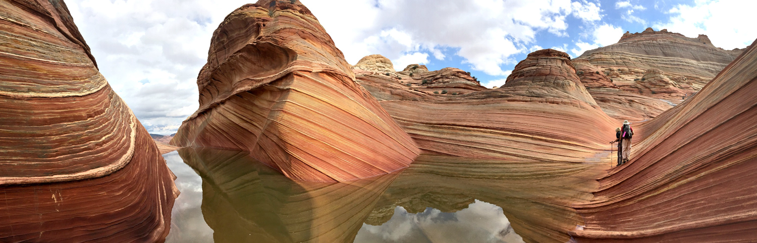 Two hikers in Coyote Buttes. The Coyote Buttes area, on the Utah/Arizona border, is most popular for a multi-colored sandstone rock formations. 