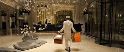 VIP Treatment - Bellhop carrying luggage through a luxury Virtuoso property.